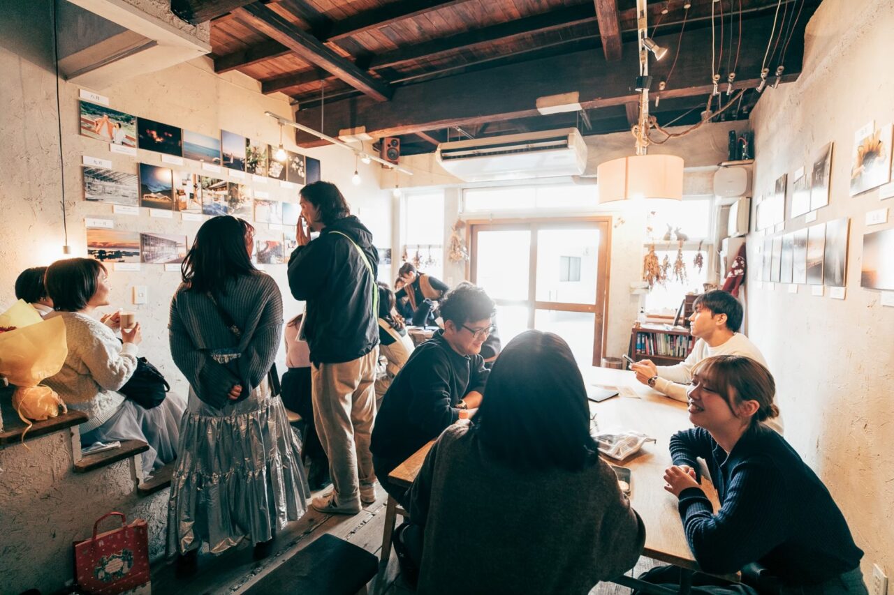 toco.の写真展で来場者が作品や会話を楽しむ様子